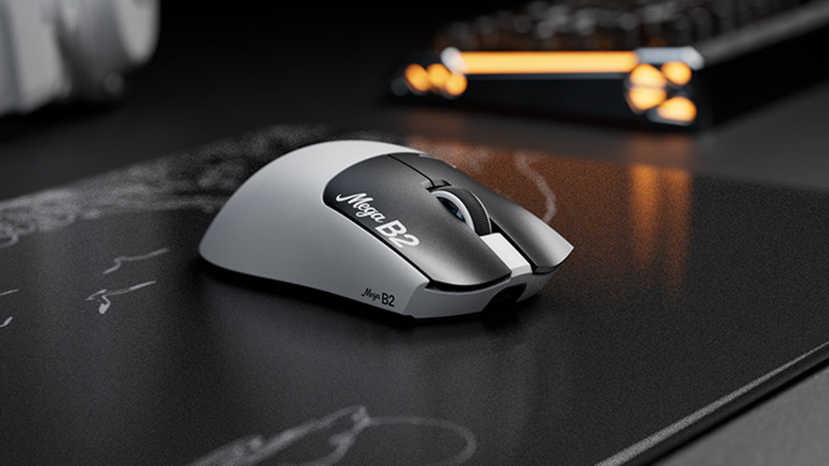 ATTACK SHARK Mega B2 gaming mouse on a black desk mat, with an orange-backlit keyboard glowing in the dark background